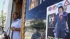 Libya -- A Libyan rebel stands by a shop window decorated with a portrait of Moammar Gadhafi with his son Seif al-Islam on his shoulders, in Tripoli, 25Aug2011